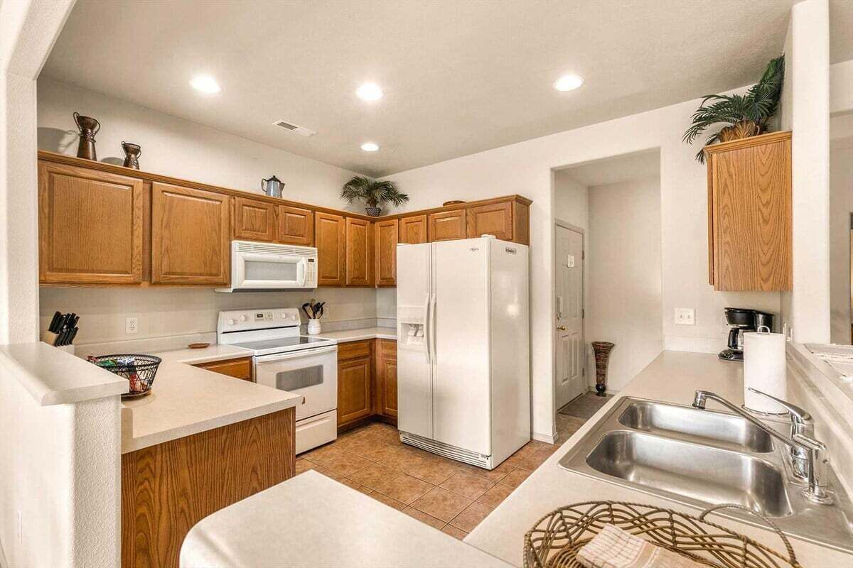 A kitchen with wooden cabinets, a white refrigerator, a microwave, a stove, and a sink.