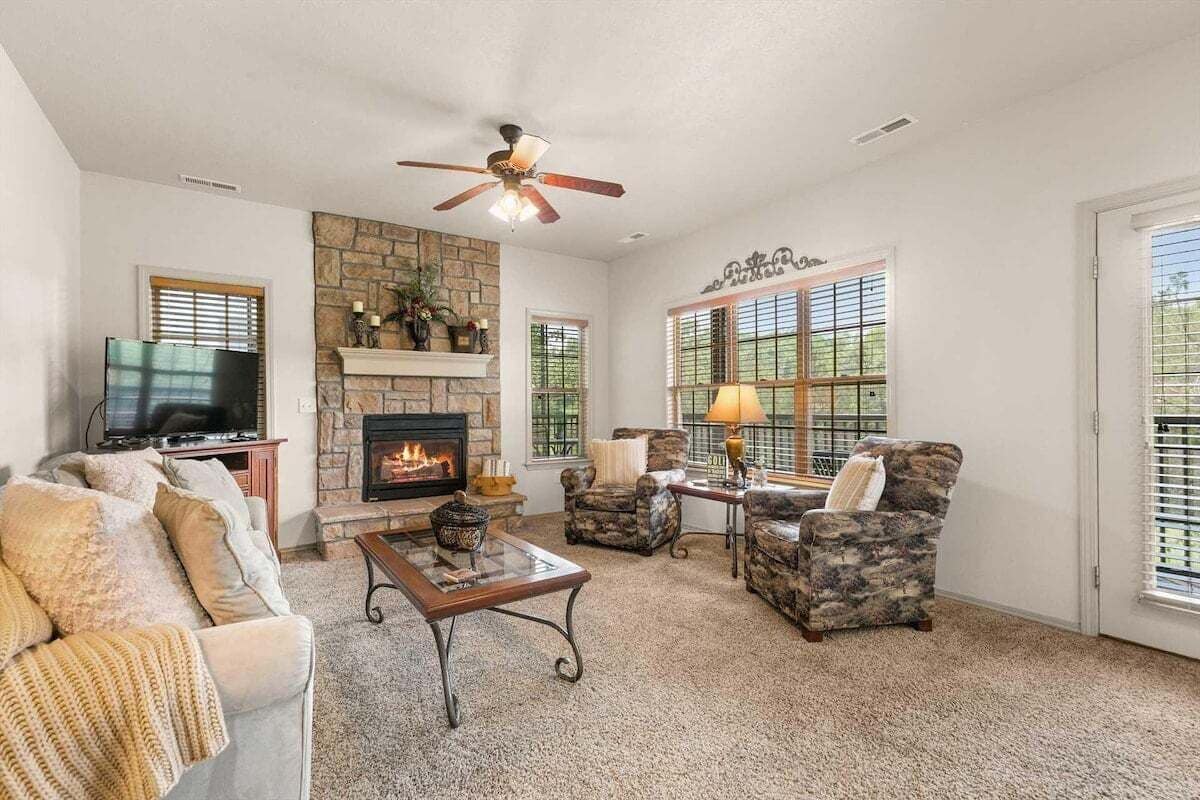 A living room with a fireplace, a ceiling fan, and a television.