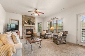 A living room with a fireplace, a ceiling fan, and a television. - StoneBridge Villa-Near Silver Dollar City-Golf Course Views- Free Daily Attraction Tickets (Branson West)