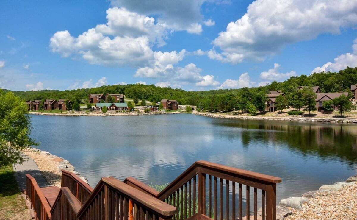 Ein Anwesen am Seeufer mit mehreren Holzhütten, einer Holzterrasse und freiem Blick auf das Wasser.