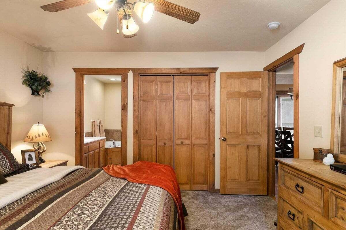 Una camera da letto con un letto, un comodino, una lampada, una ventola a soffitto e porte in legno.