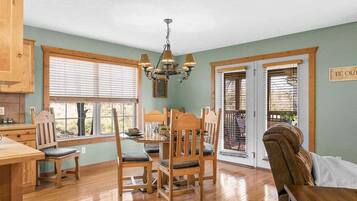 A dining area with wooden furniture, a chandelier, and a view through the windows.