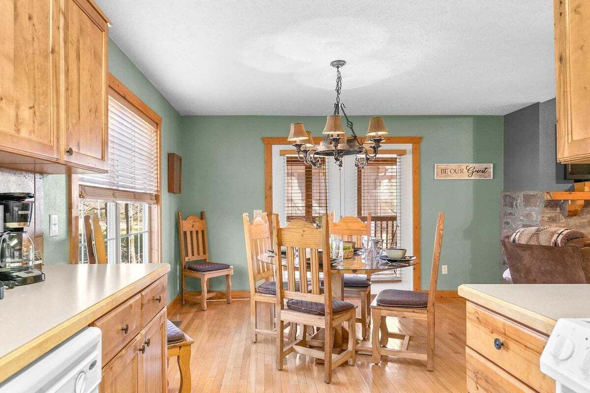 A dining area with wooden furniture, a chandelier, and a sign that reads 'BE OUR GUEST.'