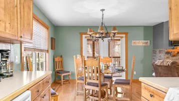 A dining area with wooden furniture, a chandelier, and a sign that reads 'BE OUR GUEST.'