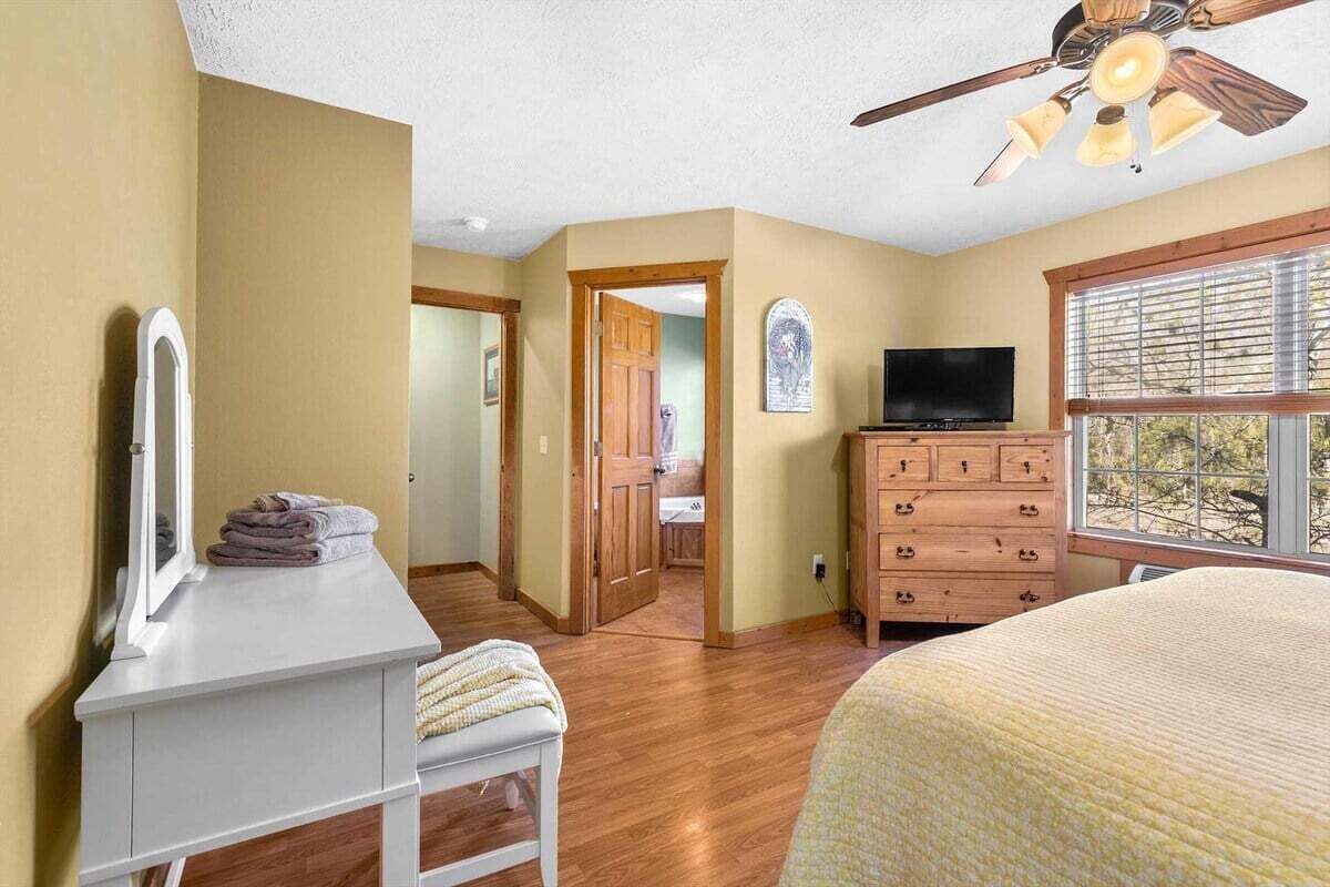 Un dormitorio con cama, cómoda, televisor y ventana con vistas.
