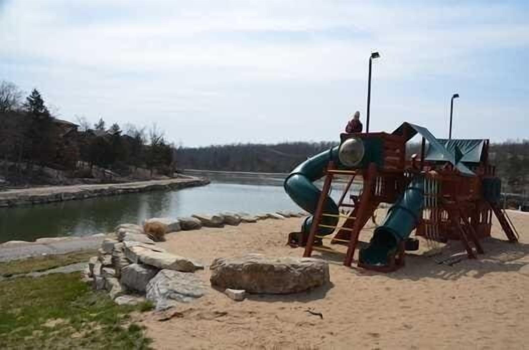 A playground with a slide and climbing structures near a body of water.