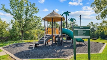 A children's play area with a slide, climbing structures, and a covered seating area.