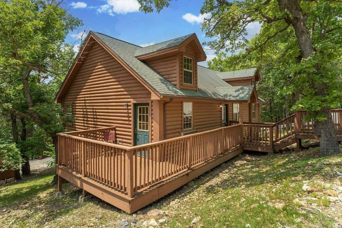 Une cabane en rondins dotée d’un balcon et d’un escalier menant à l’entrée principale.