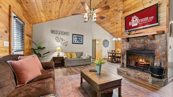 Un salon spacieux doté d’une cheminée, d’un plafond en bois et d’une pancarte d’accueil.
