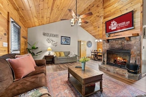 A spacious living room with a fireplace, wooden ceiling, and a welcome sign. - King Bedrooms, Resort Amenities, Free Daily Attraction Tickets (Branson)