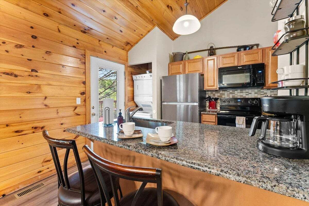 A kitchen with wooden walls, granite countertops, and modern appliances including a refrigerator, stove, and microwave.