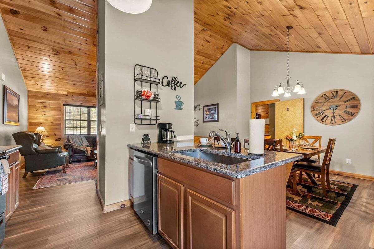 A modern kitchen with a central island, wooden cabinetry, and a built-in dishwasher.