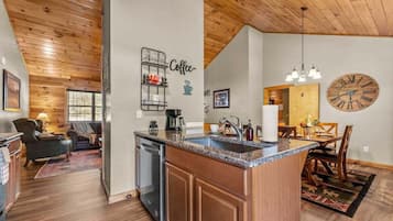 A modern kitchen with a central island, wooden cabinetry, and a built-in dishwasher.