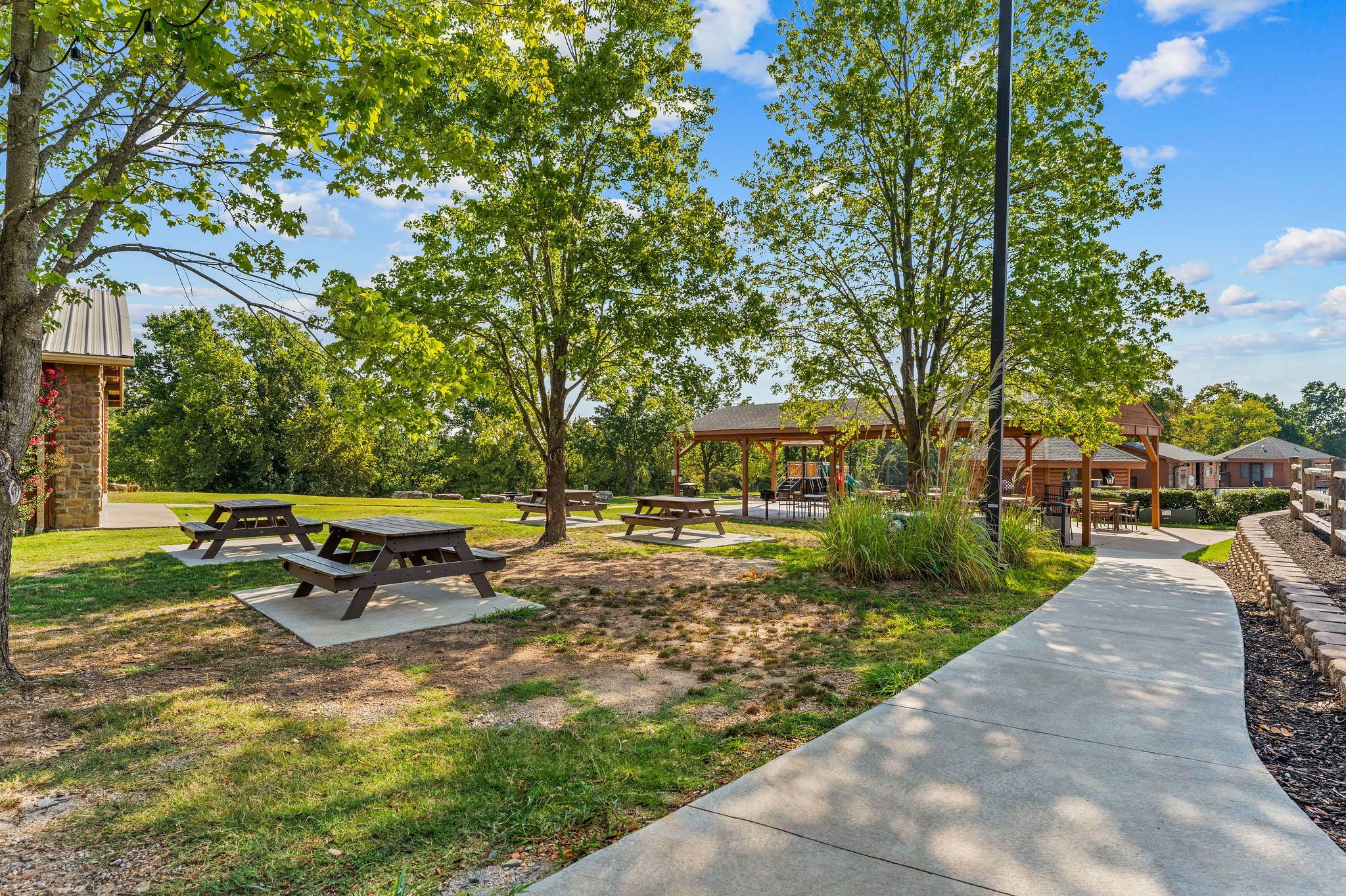 Un parque con mesas de picnic, un sendero para caminar y un edificio de fachada de piedra.