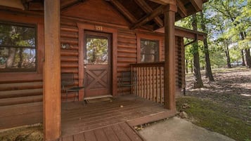 A log cabin with a porch, a door marked '153', and two chairs outside.