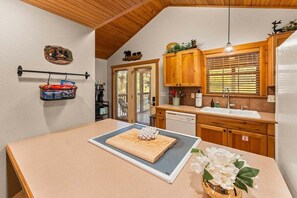 A kitchen with wooden cabinets, a countertop, a hanging basket, and a window with blinds. - StoneBridge Gated Resort-"Four Acorns Lodge"- Free Daily Attraction Tickets (Branson West)