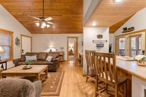 A cozy living room with a wooden ceiling, a brown leather sofa, a wooden dining table, and a wooden chair. - StoneBridge Gated Resort-"Four Acorns Lodge"- Free Daily Attraction Tickets (Branson West)
