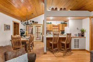 A wooden interior with a dining area, kitchen, and seating space. - StoneBridge Gated Resort-"Four Acorns Lodge"- Free Daily Attraction Tickets (Branson West)