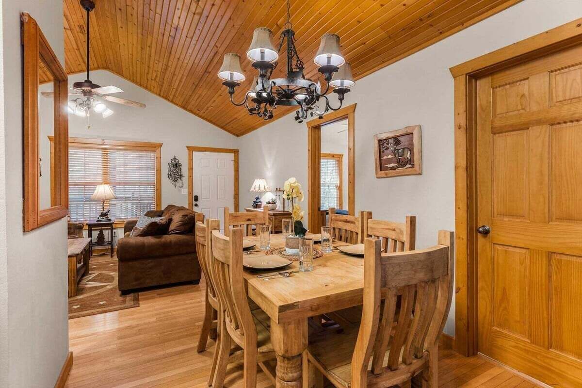 Comedor con mesa y sillas de madera, una lámpara de araña y un ventilador de techo.