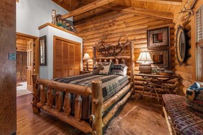 Interno di una baita in legno con un letto di legno, un camino e arredamento rustico.