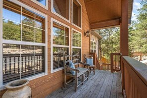 A wooden deck with a railing, a covered porch, and a view of the surrounding landscape. - Walk In Lodge on Golf Course_Near SDC_Foosball Game_Screened In Porch_Free Attraction Tickets (Branson West)