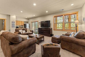 A living room with brown sofas, a coffee table, a TV, and a window with blinds. - Walk In Lodge on Golf Course_Near SDC_Foosball Game_Screened In Porch_Free Attraction Tickets (Branson West)