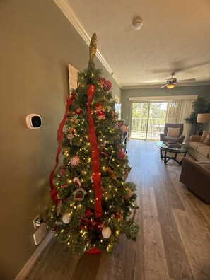 A living room with a Christmas tree, a ceiling fan, and a sliding glass door leading to a balcony. - Great Condo Just 5 Minutes to Branson!- Free Daily Attraction tickets (Branson)