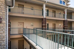 Een meerlaags gebouw met een balkon op de begane grond, voorzien van een metalen hekwerk en een bakstenen pilaar.