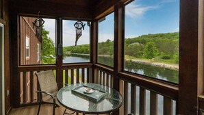Ein von Glas umschlossener Balkon mit Tisch, Stühlen und Dekoration.