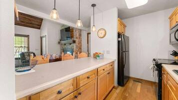 A kitchen with wooden cabinets, a refrigerator, a microwave, and pendant lighting.