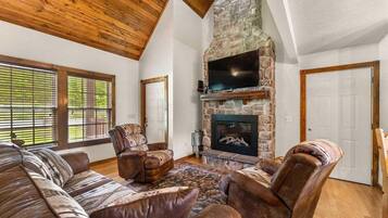 A living room with a stone fireplace, leather sofas, and a television.