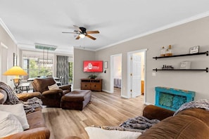 Ein modernes Wohnzimmer mit einer Couch, einem Hocker und einem an der Wand befestigten Fernseher.