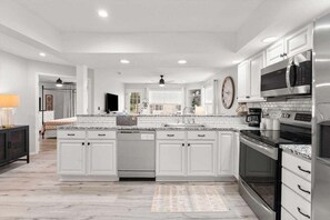 A modern kitchen with white cabinetry, stainless steel appliances, and a marble countertop. - New Beautifully Renovated Condo w Great Pool View! Free Daily Attraction Tickets (Branson)