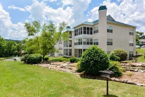 A multi-story building with a flat roof, large windows, and a landscaped front yard with trees and shrubs. - New Beautifully Renovated Condo w Great Pool View! Free Daily Attraction Tickets (Branson)