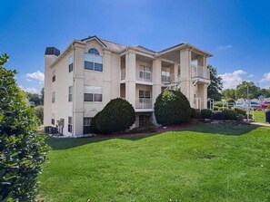 A multi-story residential building with a flat roof, balconies, and a well-maintained lawn. - New Beautifully Renovated Condo w Great Pool View! Free Daily Attraction Tickets (Branson)