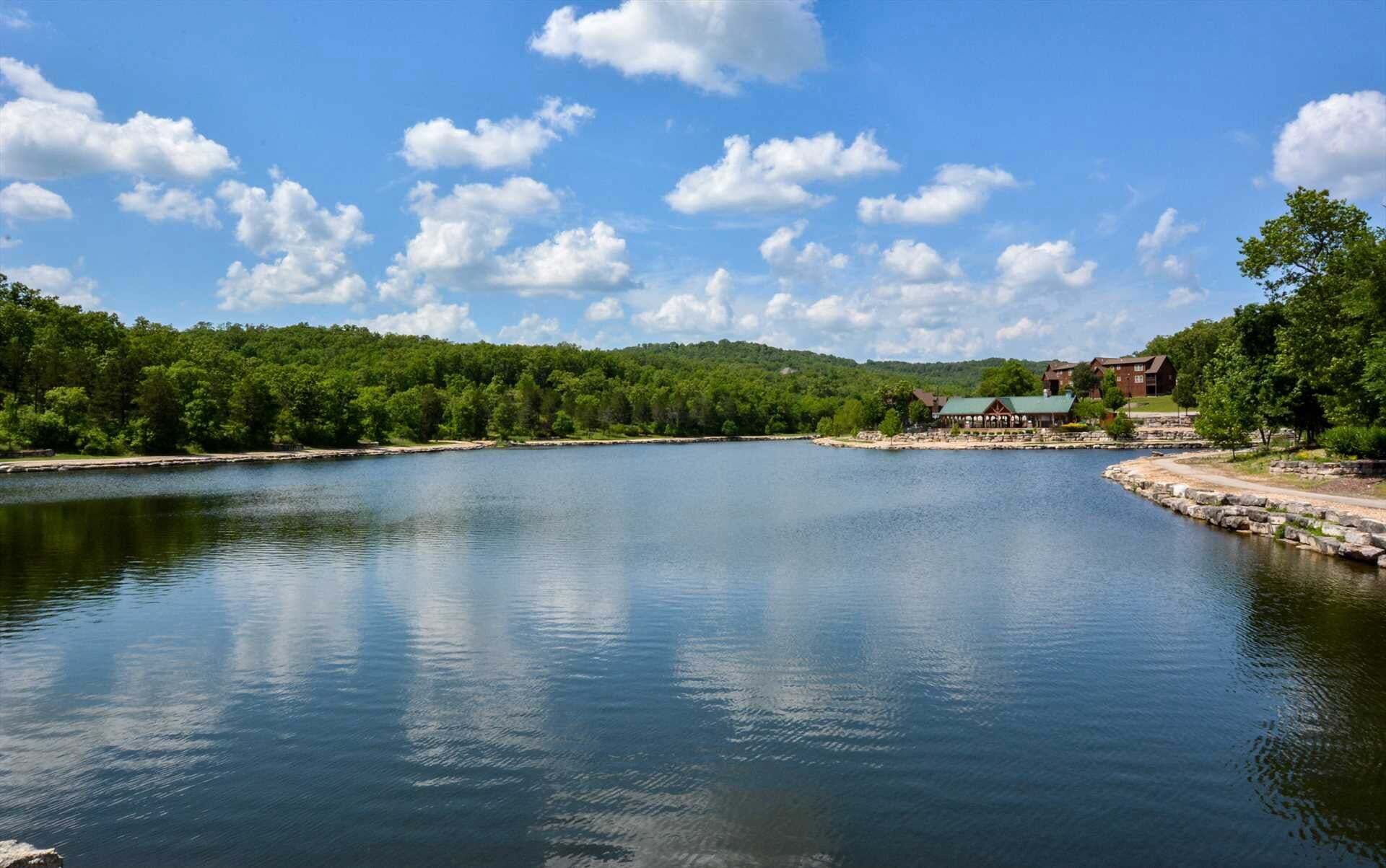 Ein ruhiger See mit einer Holzsteg, umgeben von dichtem Grün und einem klaren Himmel.