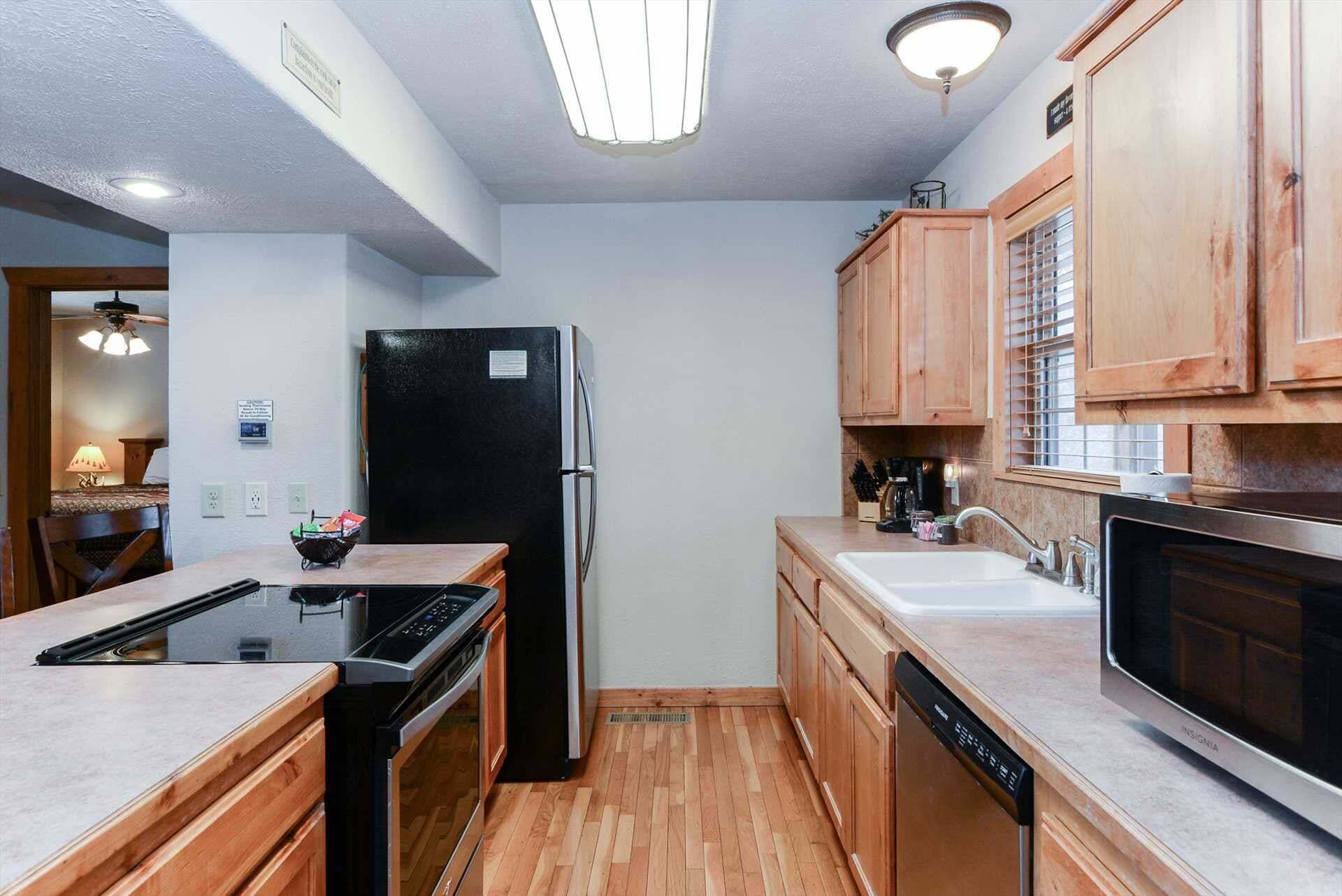 A kitchen with wooden cabinets, a black refrigerator, a dishwasher, and a microwave.