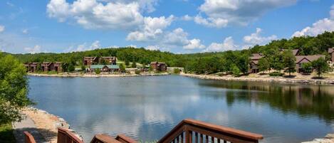 A lakeside view with wooden walkways leading to a building complex.