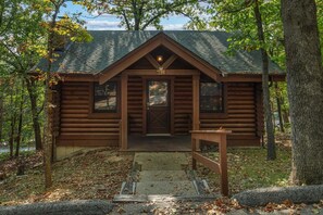 A log cabin with a front porch, a small table, and a bench. - Genuine Log Cabin_Gated Community_Ample Amenities_Free Daily Attraction Tickets (Branson)