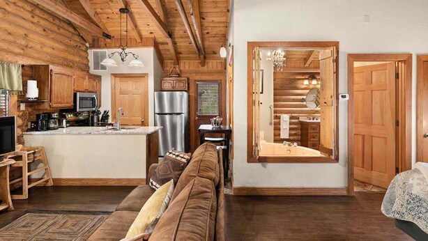 Interior acogedor de una cabaña de madera con cocina, comedor y sala de estar con sofá.