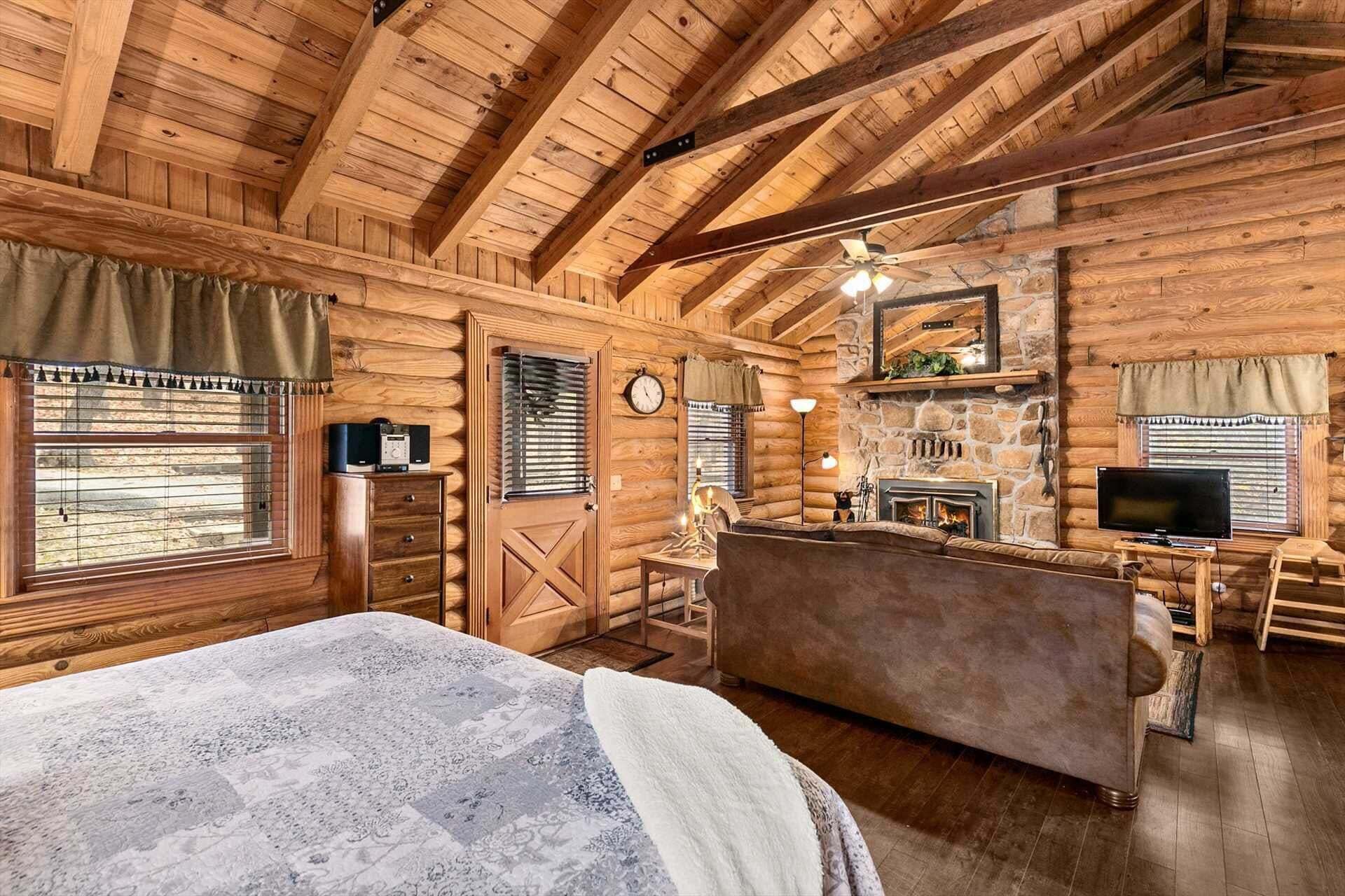L’intérieur d’une cabane en rondins, avec un lit, une cheminée, un téléviseur et des murs en bois.