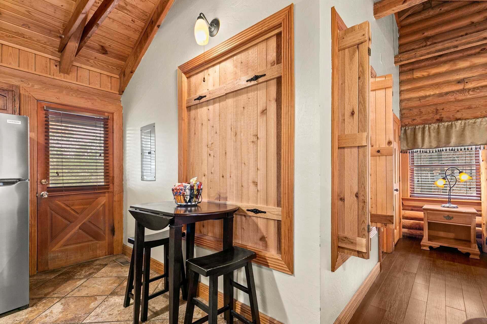 A kitchen with wooden cabinets, a refrigerator, a dining table with two chairs, and a window with blinds.