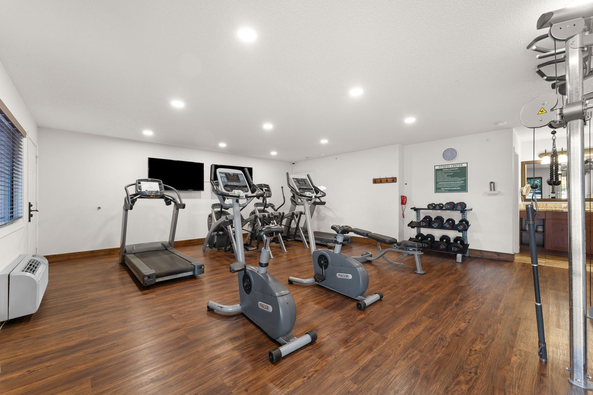 A fitness center with treadmills, elliptical machines, and free weights.