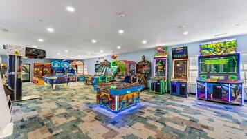 A room with arcade games, a carpeted floor, and a ceiling with recessed lighting.