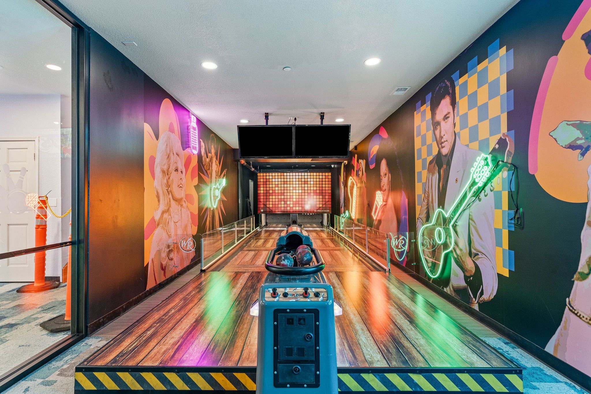 A bowling alley with wooden floors and colorful murals on the walls.