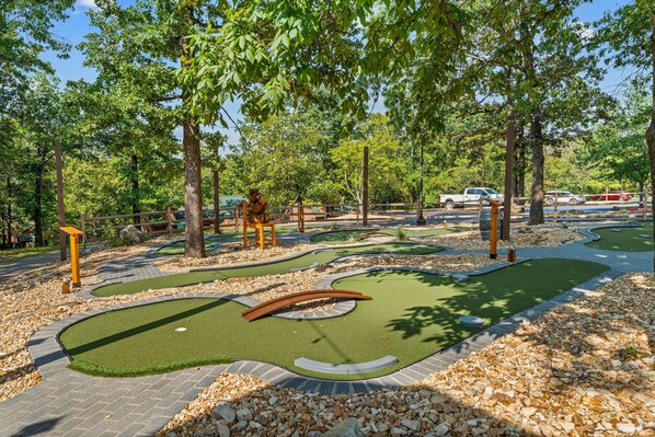 Ein Minigolfplatz mit Puttinggrün, Sandfällen und einer Holzbank.
