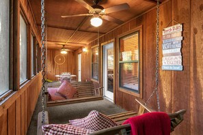 Ein gemütlicher Veranda-Bereich mit Holzwänden, einem Deckenventilator und einem Schild mit Verandabestimmungen.