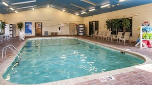 Une piscine intérieure avec un panneau indiquant qu’il est interdit de plonger, un poste de surveillance pour les sauveteurs et des chaises longues.