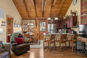 A cozy cabin interior with a dining area, kitchen, and living room.