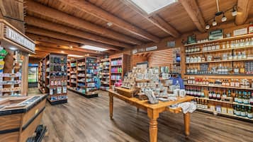 Un intérieur en bois avec une table centrale où sont exposés divers objets, des étagères remplies de bouteilles et une pancarte indiquant : « Paix, amour, musique country ».